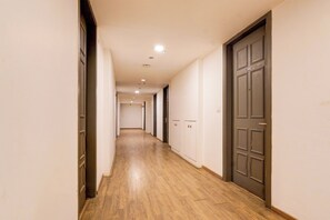 Un passadís amb sòl de fusta, portes fosques i il·luminació empotrada.