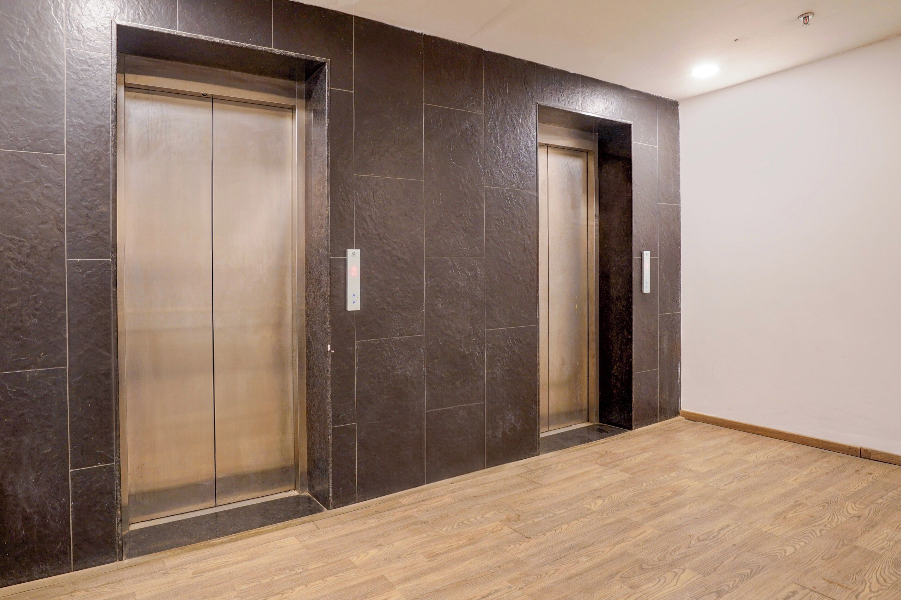 Un pasillo con dos ascensores y piso de madera.