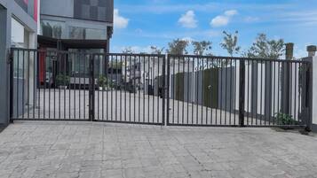Una entrada con acceso restringido y un camino pavimentado que conduce a un edificio.