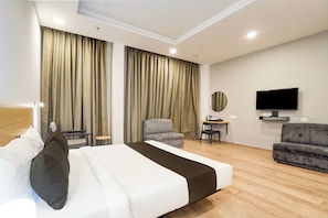 Une chambre d’hôtel avec un lit, un canapé, une télévision et des rideaux.