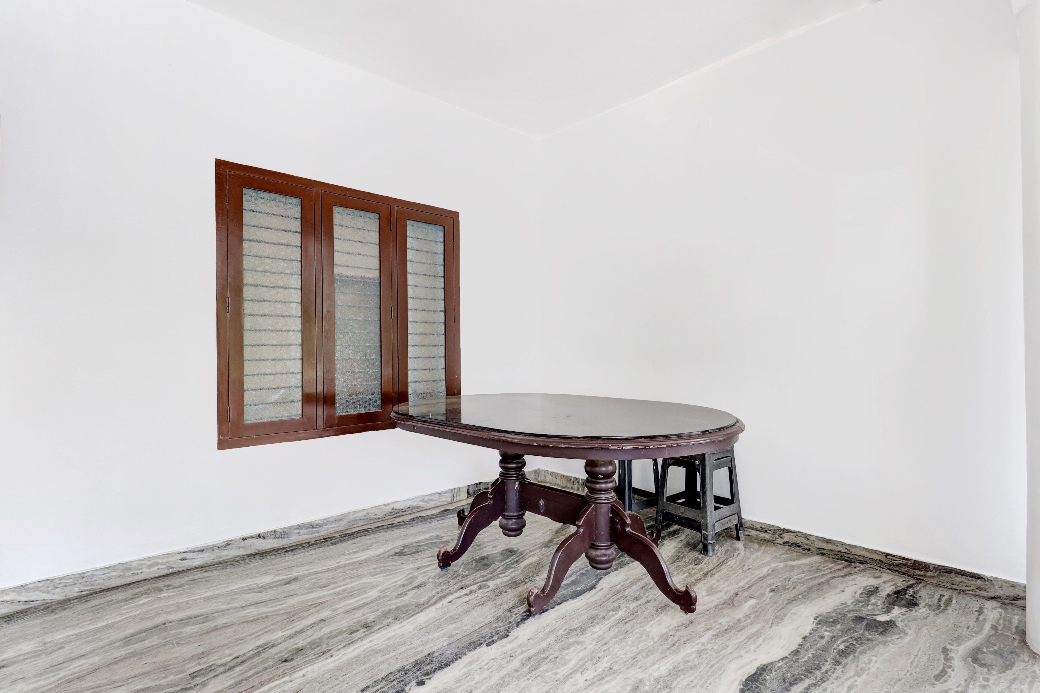 A corner room with a round table, a wooden cabinet, and a window with frosted glass panels.