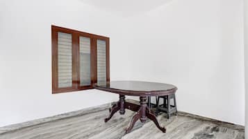 A corner room with a round table, a wooden cabinet, and a window with frosted glass panels.