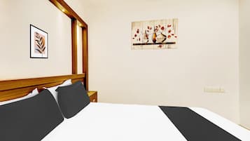 A hotel room with a large bed, a wooden headboard, a nightstand, and a wall-mounted painting.