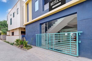 Exterior moderno de un hotel con fachada azul y amarilla, entrada con portón y escalera que conduce a la entrada.