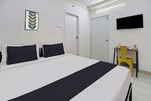 A hotel room with a bed, a desk, a chair, a TV, and a door. - OYO Hotel O Amaravathi Road Annapurna (Guntur)