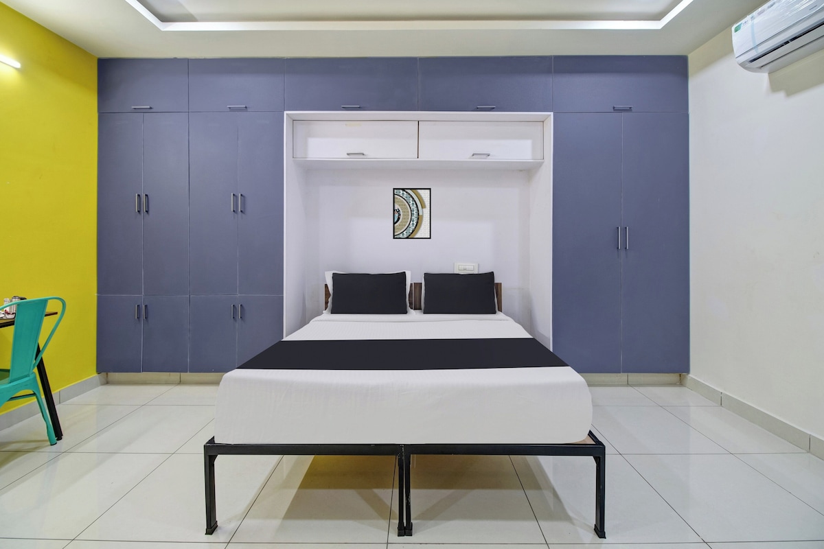 A bedroom with a bed, a wardrobe, a chair, and an air conditioning unit.