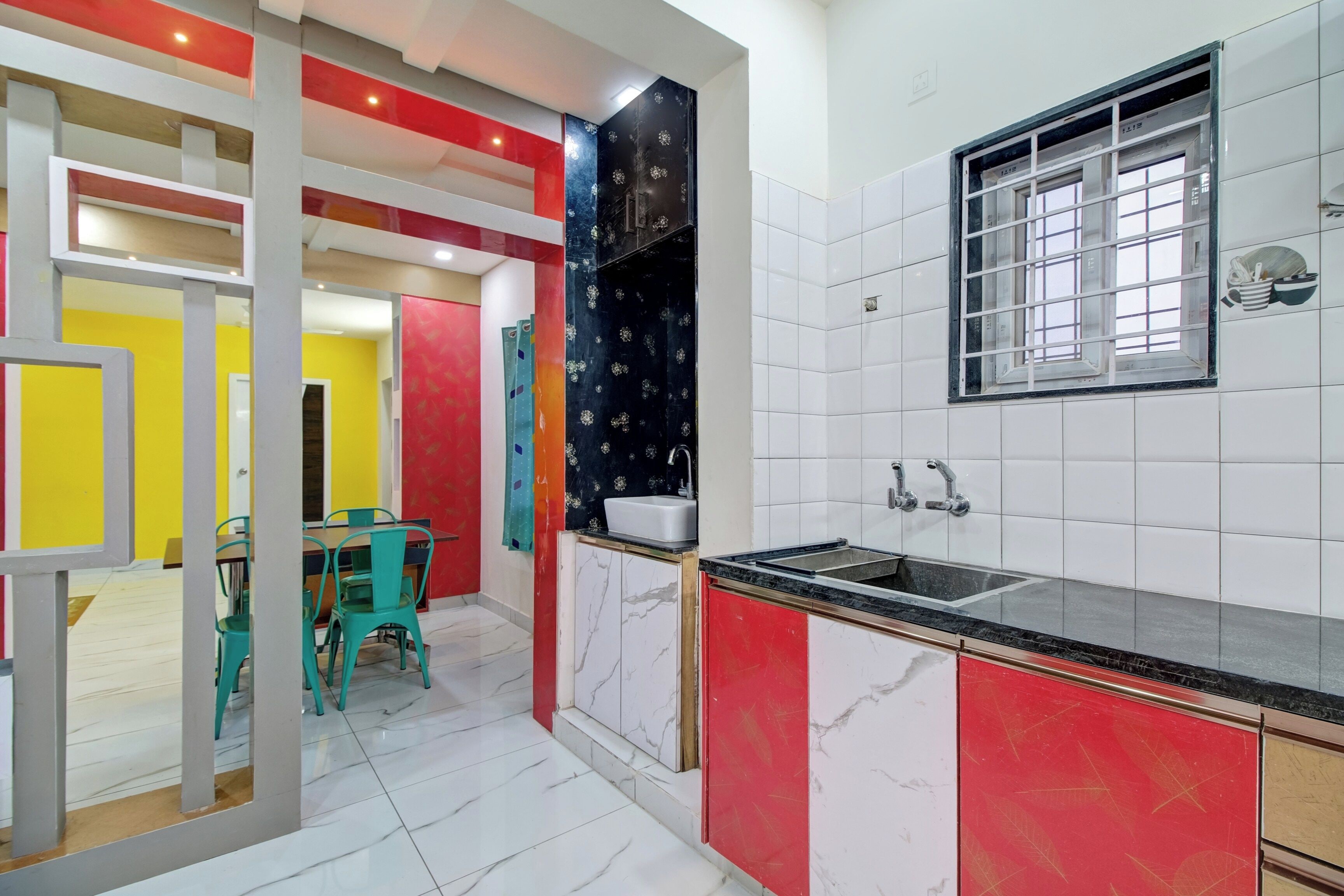 A kitchen with white and red cabinets, a black countertop, and a window with a view.