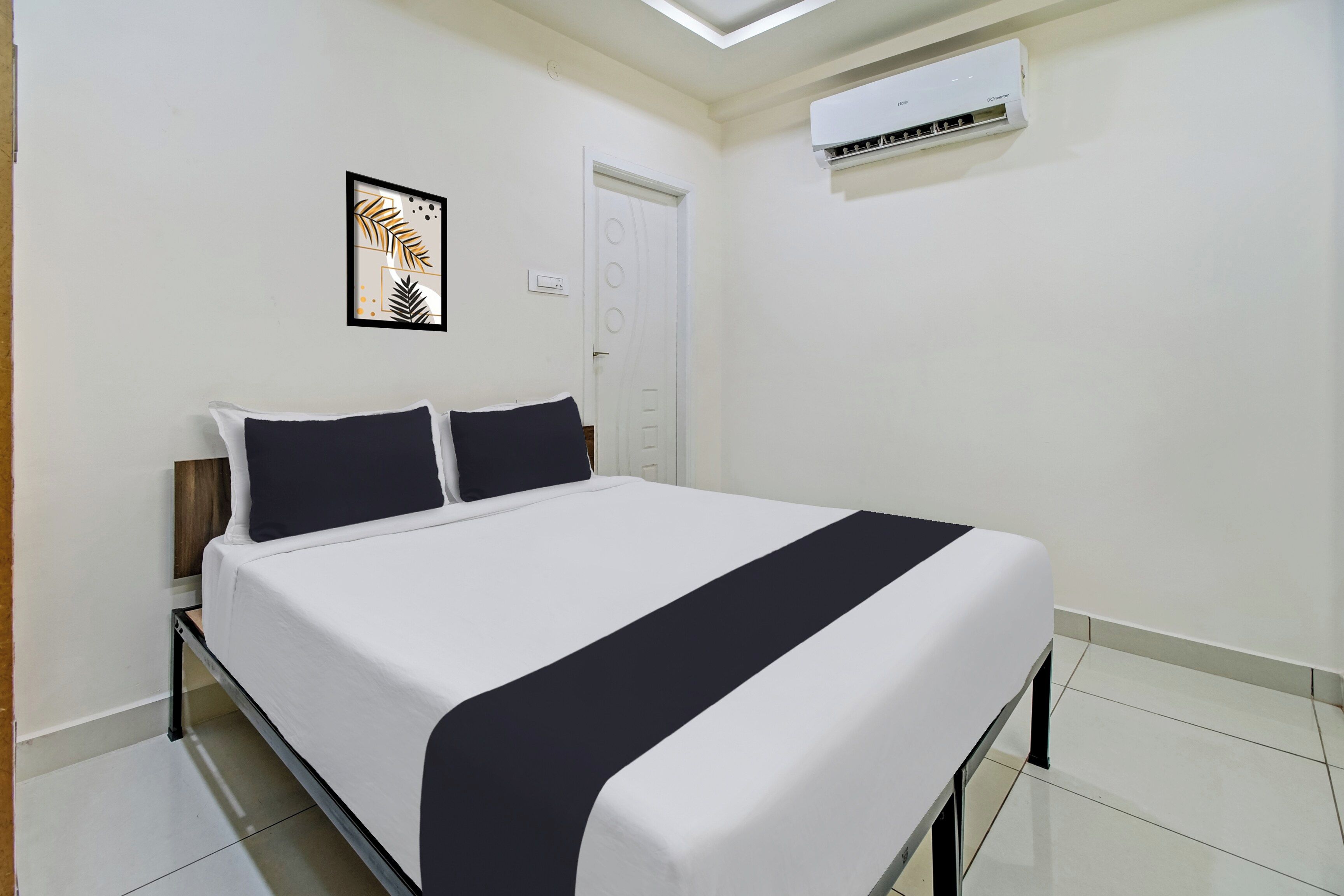 A hotel room with a bed, a wall-mounted air conditioner, and a door.