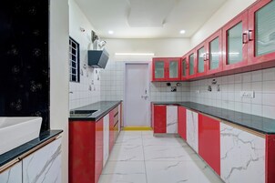 Cocina con armarios rojos, azulejos blancos y encimera negra.