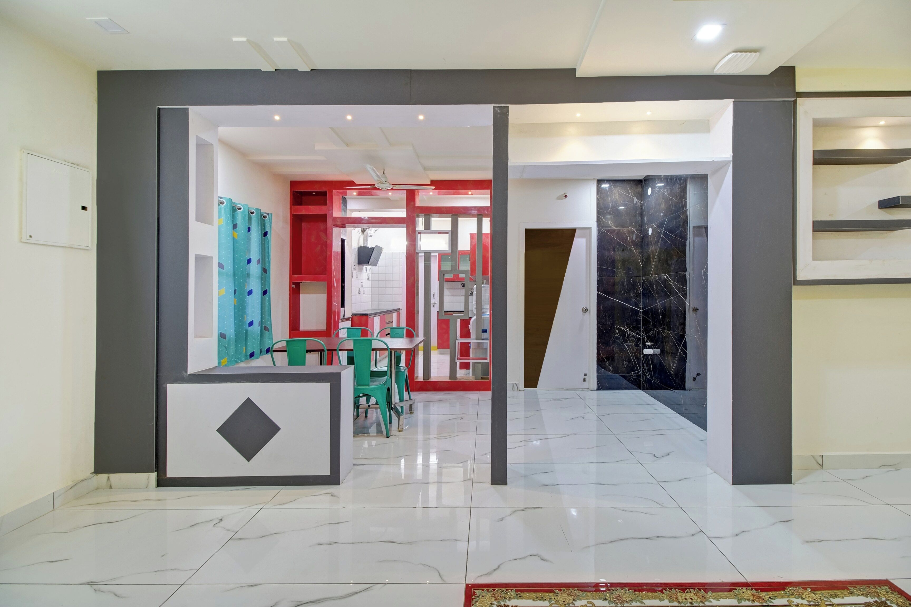 Un interior moderno con una recepción, un comedor con sillas y un pasillo que conduce a una habitación con pared de mármol negro.