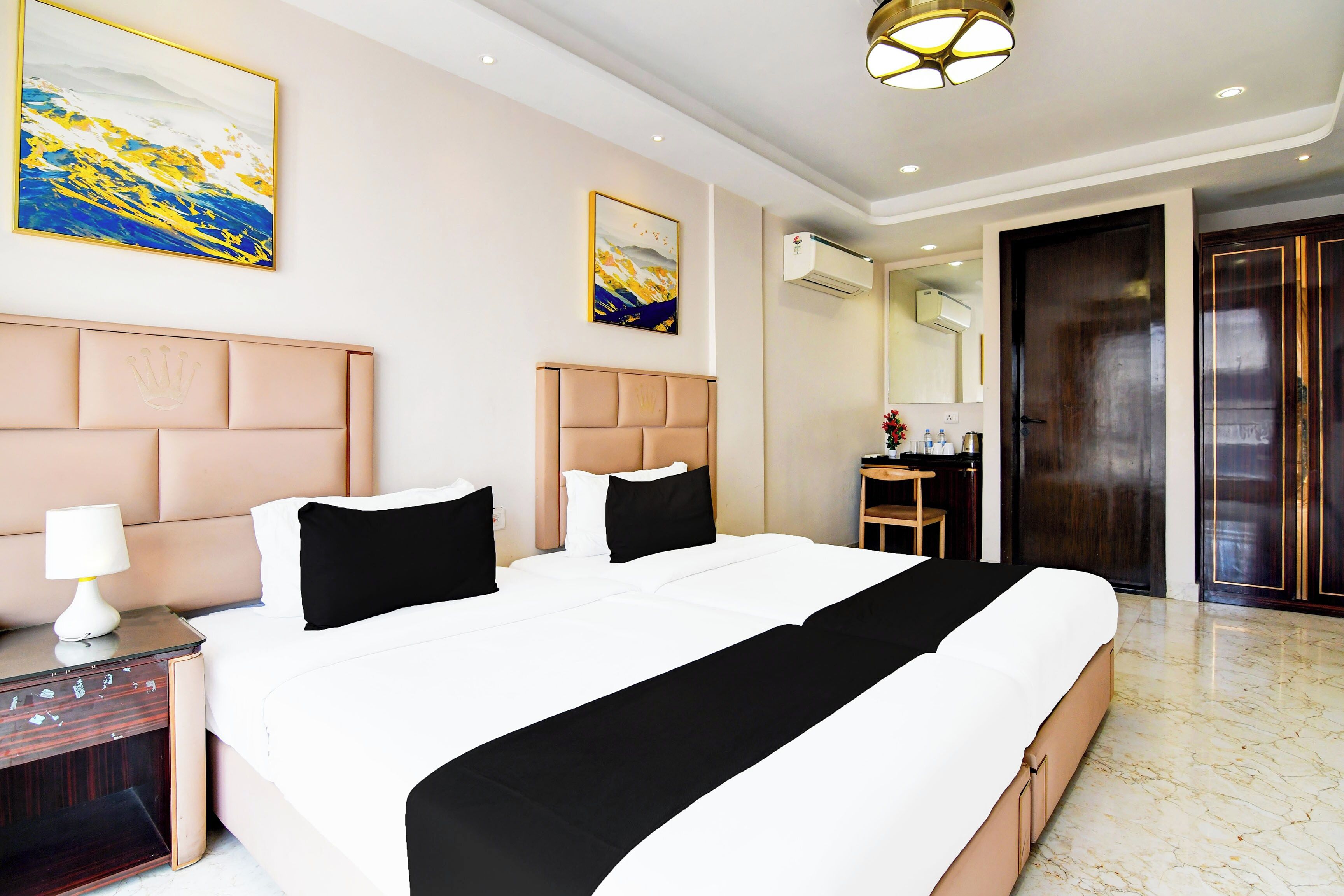 Una habitación de hotel con una cama grande, mesitas de noche, una lámpara y obras de arte en las paredes.