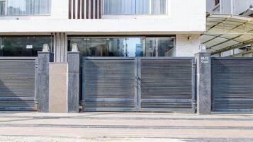 A building with a closed metal gate, a paved entrance, and a clear sky.