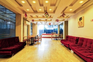 A hotel lobby with a high ceiling, multiple tables and chairs, and a red sofa. - Townhouse New Town (Barasat)