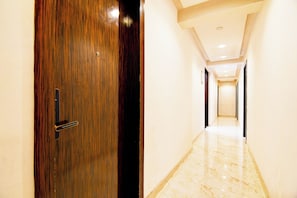Un pasillo con puerta de madera y suelo de mármol.