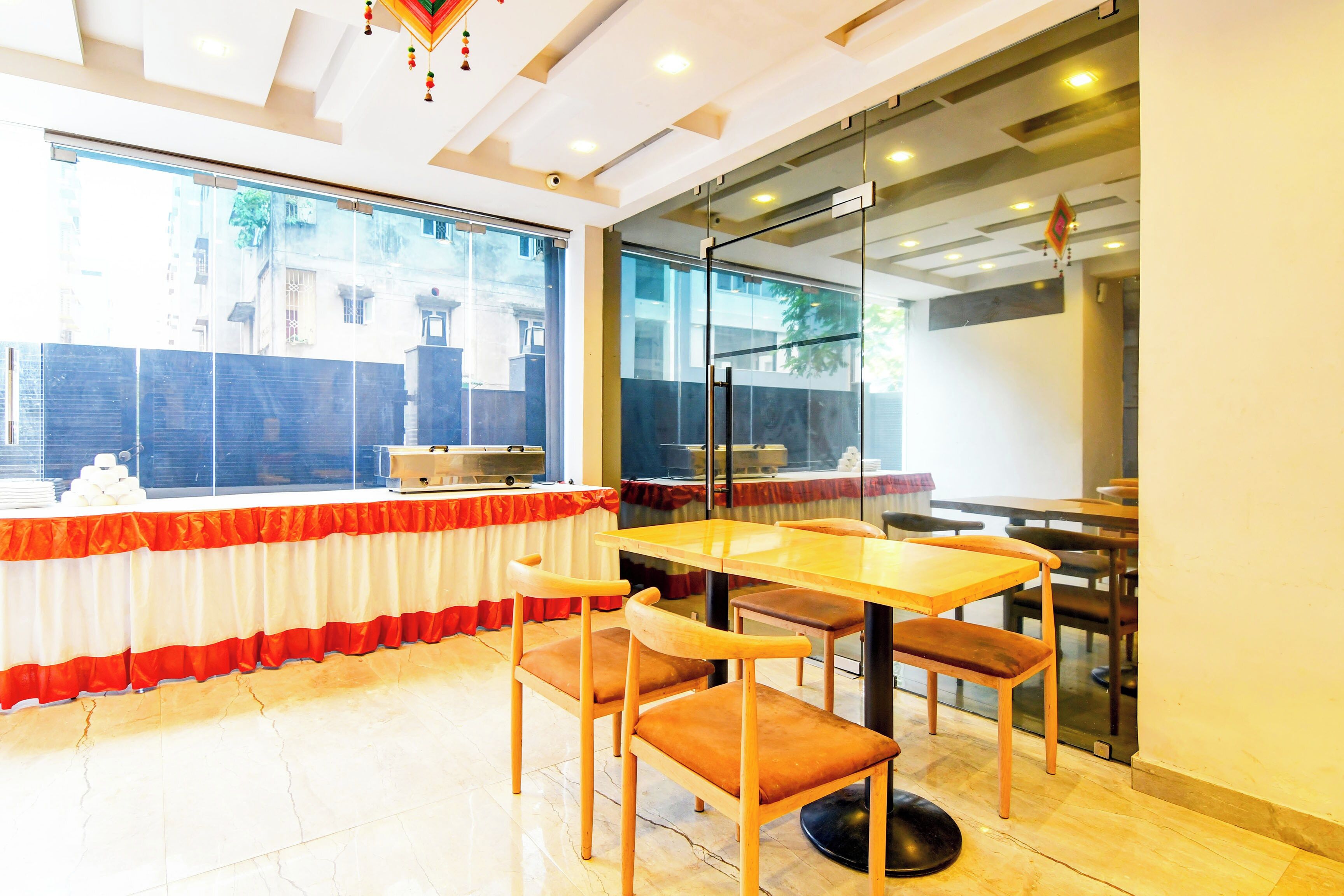 A dining area with a table and chairs, a window with a view of buildings, and a glass partition.