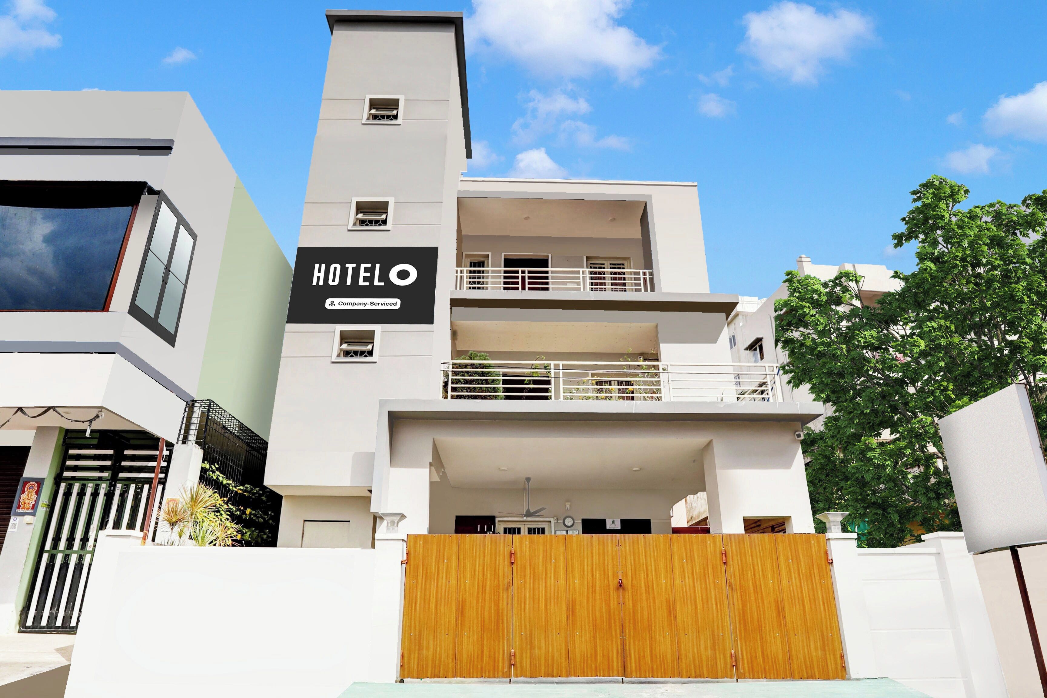 A modern hotel with a prominent 'HOTEL' sign, a gated entrance, and a clear blue sky.