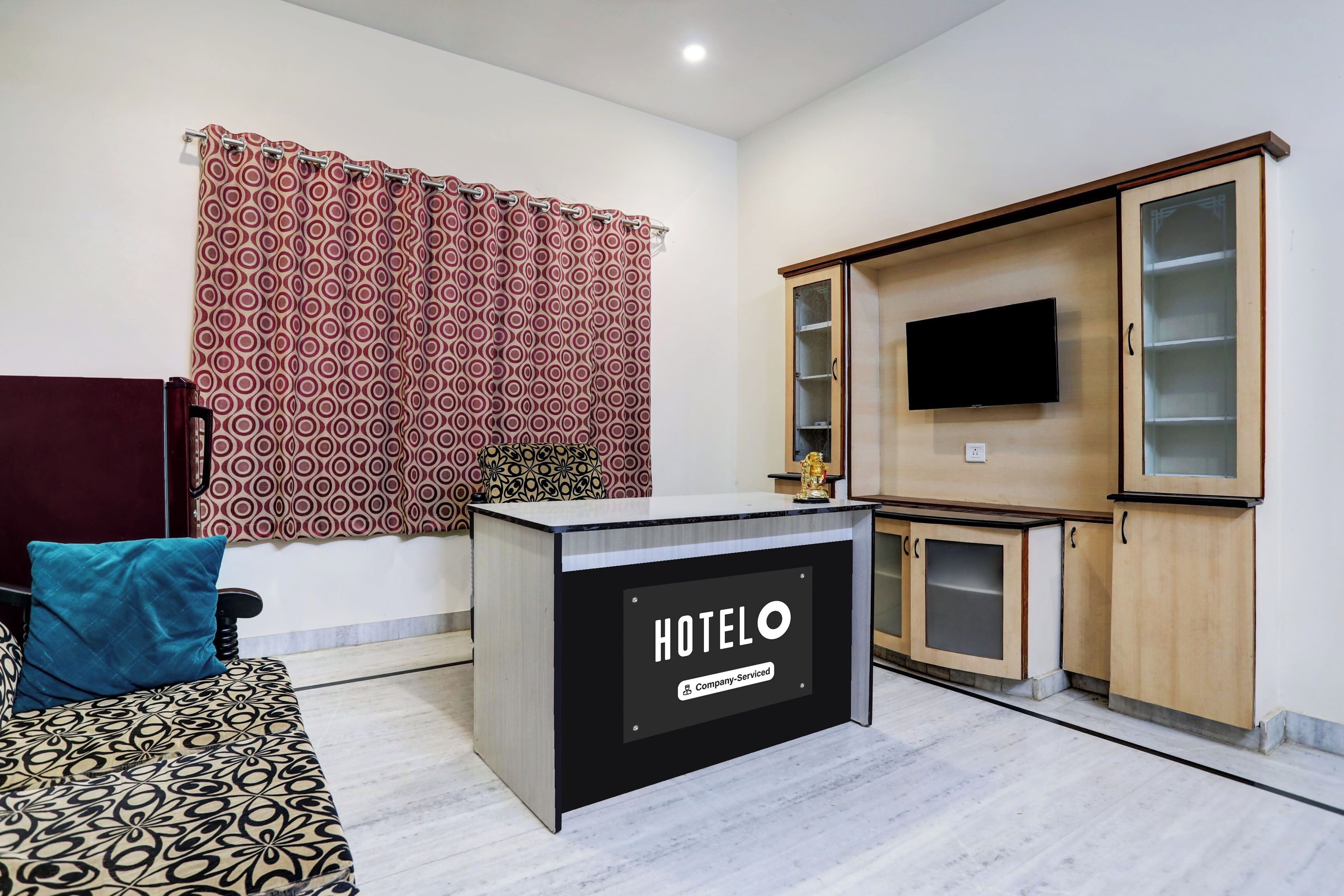 A hotel reception desk with a sign reading 'HOTELO Company Serviced'.