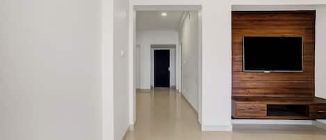 Un pasillo con una televisión de pantalla plana montada sobre un panel de madera, que conduce a una habitación oscura.