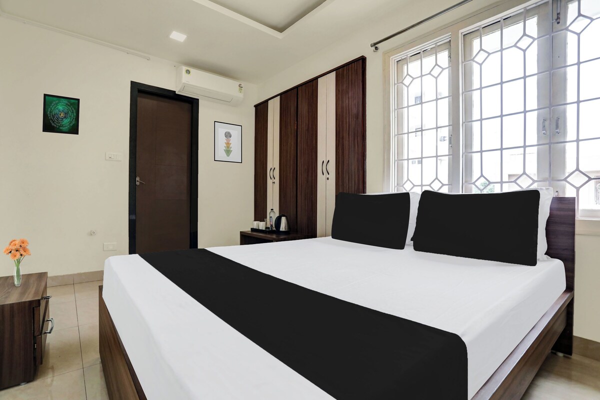 Habitación de hotel con una cama grande, un escritorio, una silla, una ventana con vistas y una puerta.