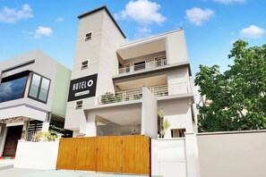Un hotel moderno con un llamativo letrero que dice 'HOTEL', varios balcones y una entrada protegida por una reja.