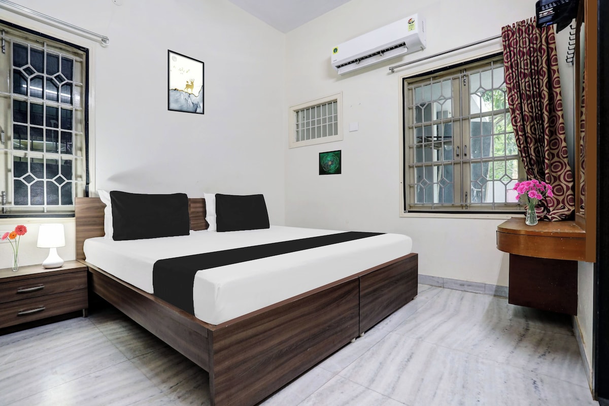 Una camera da letto moderna con un letto grande, un comodino, una lampada sul tavolino e una finestra con tende, oltre a un condizionatore d'aria.