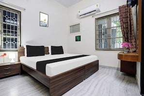 Una camera da letto moderna con un letto grande, un comodino, una lampada sul tavolino e una finestra con tende, oltre a un condizionatore d'aria.