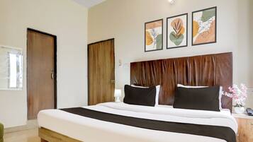 Una habitación de hotel con una cama grande, un cabecero de madera y tres obras de arte enmarcadas en la pared.