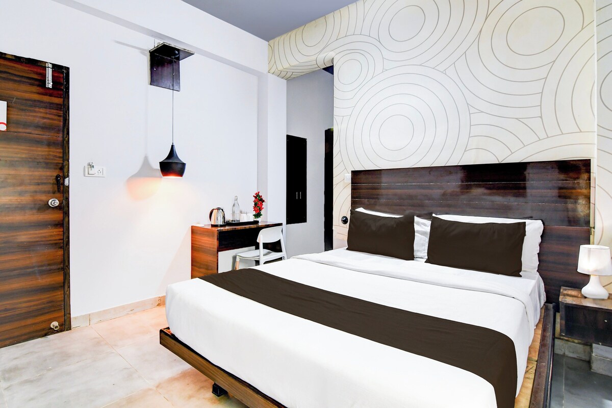 Un dormitorio moderno con una cama grande, mesitas de noche, un escritorio y un televisor montado en la pared.