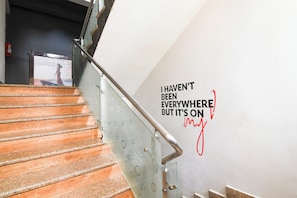 Una escalera con barandilla metálica y una pared con una cita inspiradora.