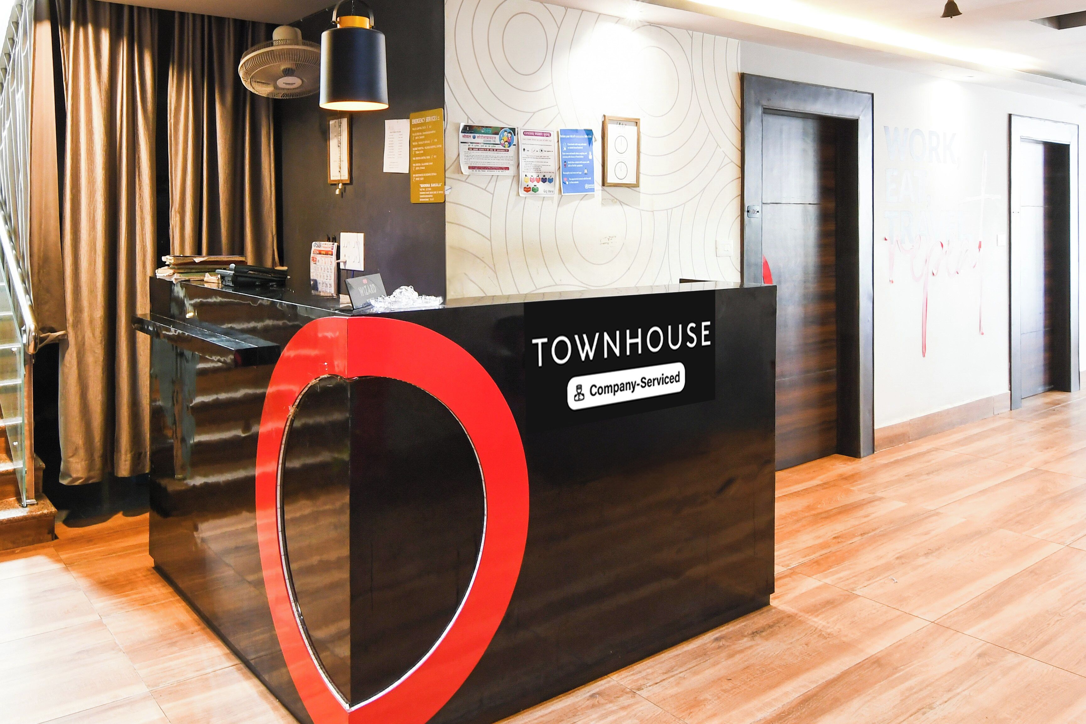 Un comptoir d’accueil au design noir et rouge, portant l’inscription « TOWNHOUSE, services aux entreprises ».