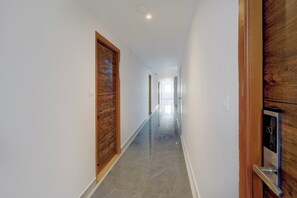 Un pasillo con puertas de madera, suelo de mármol y vista a otra habitación.