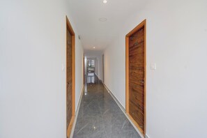 A hallway with wooden doors, a tiled floor, and a ceiling light. - Hotel O Zest Inn (Hyderabad)