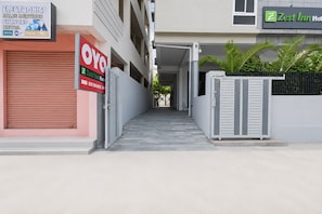 Un estrecho callejón que conduce a una entrada con portón y un letrero de OYO.