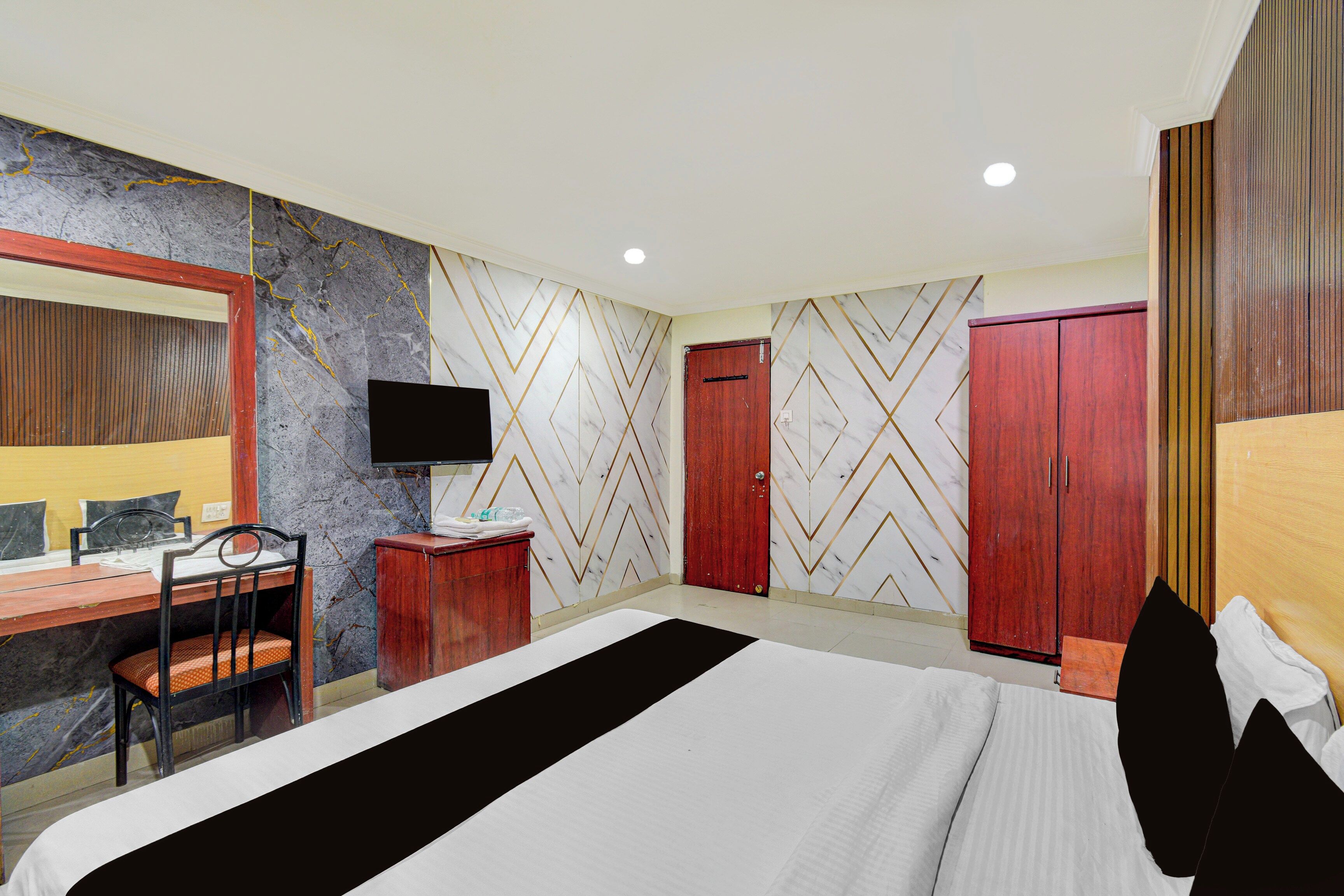 Una habitación de hotel con una cama, un escritorio con una silla, un televisor y un armario.