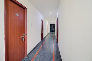 Un pasillo con puertas de madera, suelo de baldosas y una verja al final.