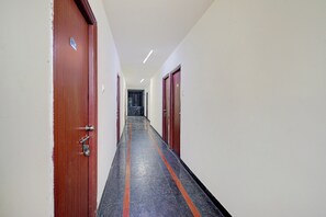 A corridor with doors on both sides, a tiled floor, and a ceiling with recessed lighting. - Hotel O Dinamo Comfort Stay (Hyderabad)