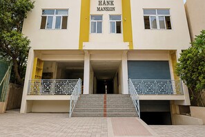 A building with a sign reading 'HANK MANSION' above the entrance, featuring a double door and a set of stairs leading up to it. - Hotel O Dinamo Comfort Stay (Hyderabad)