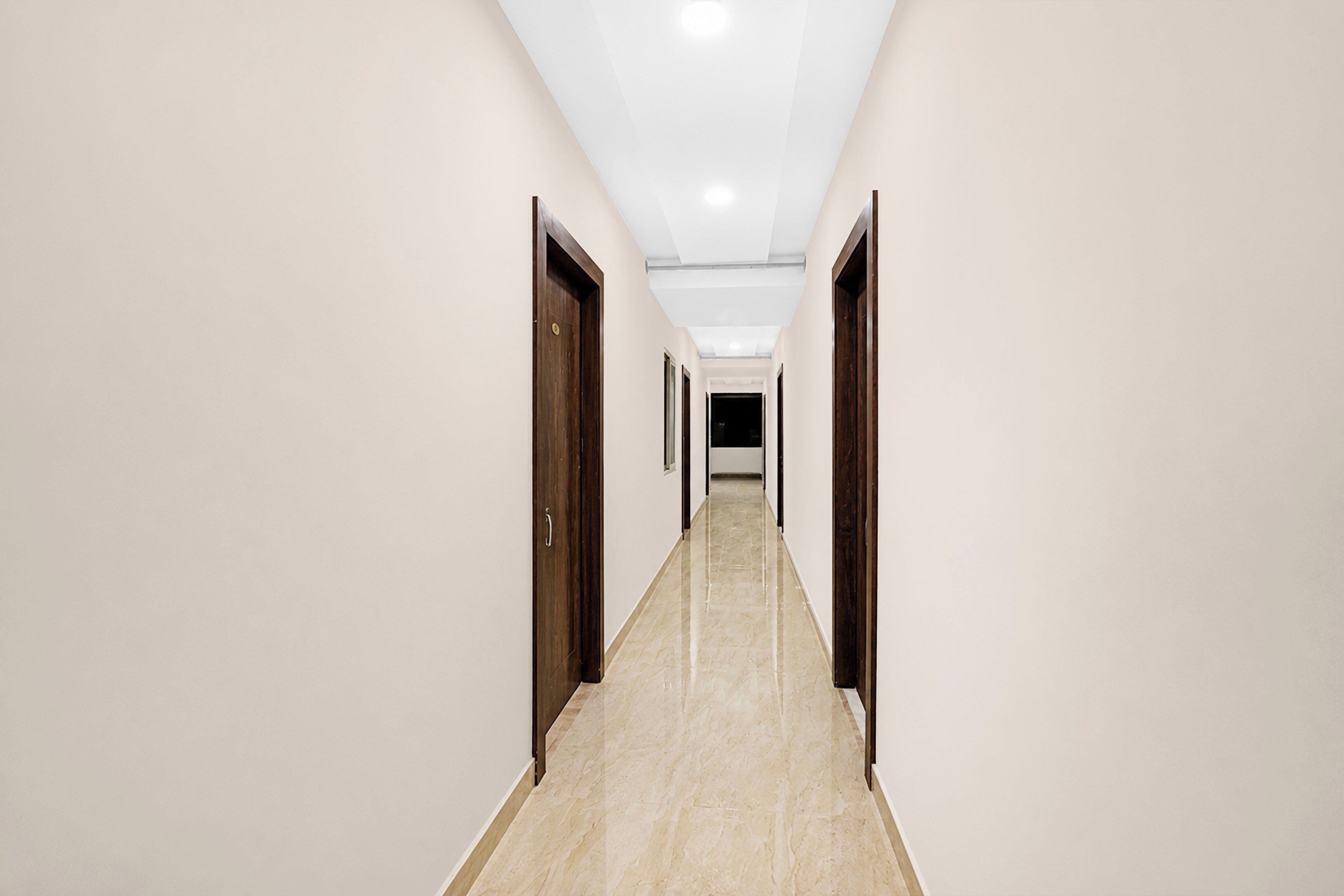 A long, narrow hallway with doors on both sides, leading to a dark room at the end.
