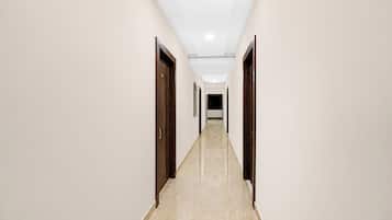 A long, narrow hallway with doors on both sides, leading to a dark room at the end.