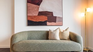 Una habitación con un sofá gris, un cuadro abstracto grande y una lámpara de pie.