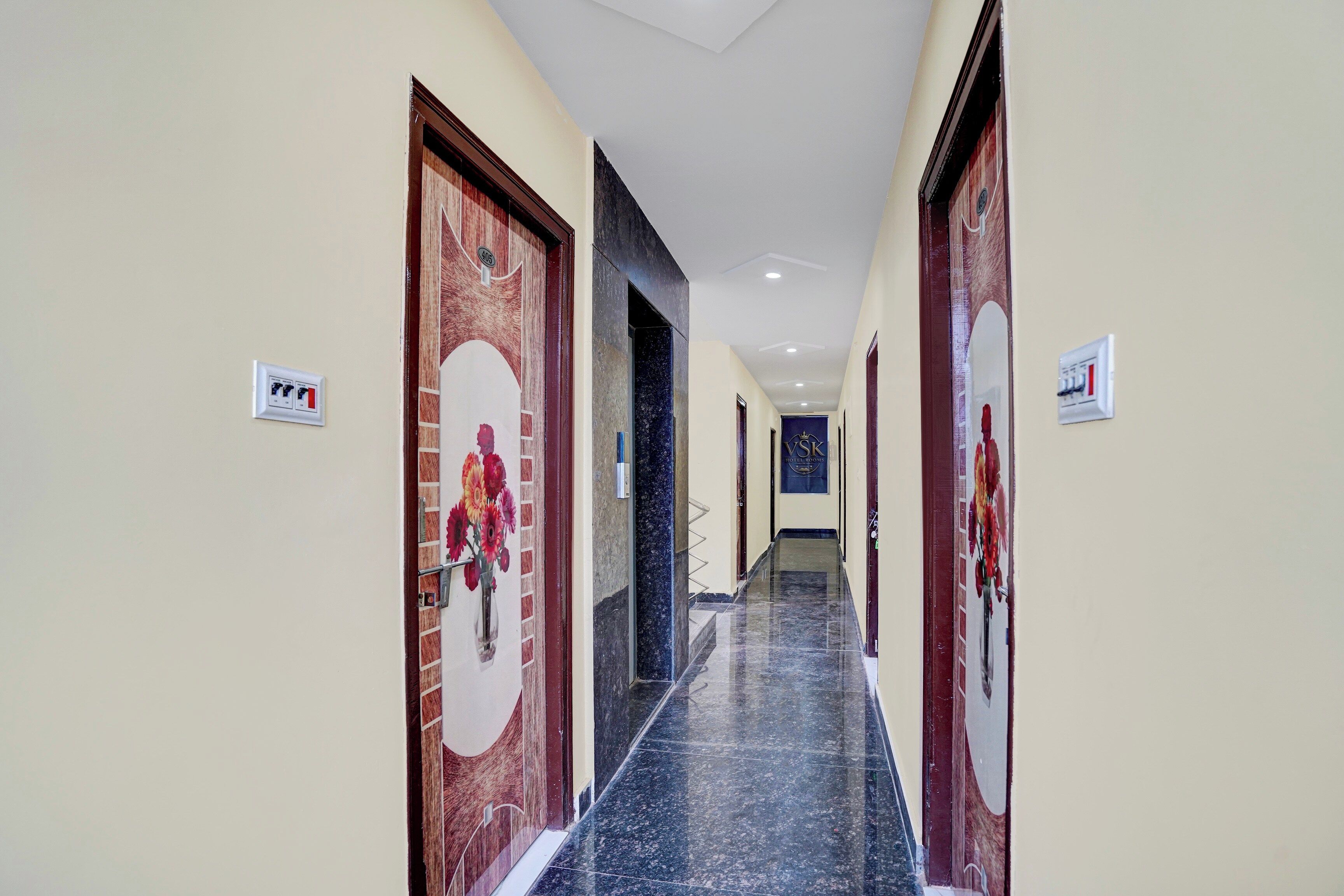 Un pasillo de hotel con suelo de mármol, puertas de madera y un cartel que indica la habitación número 405.