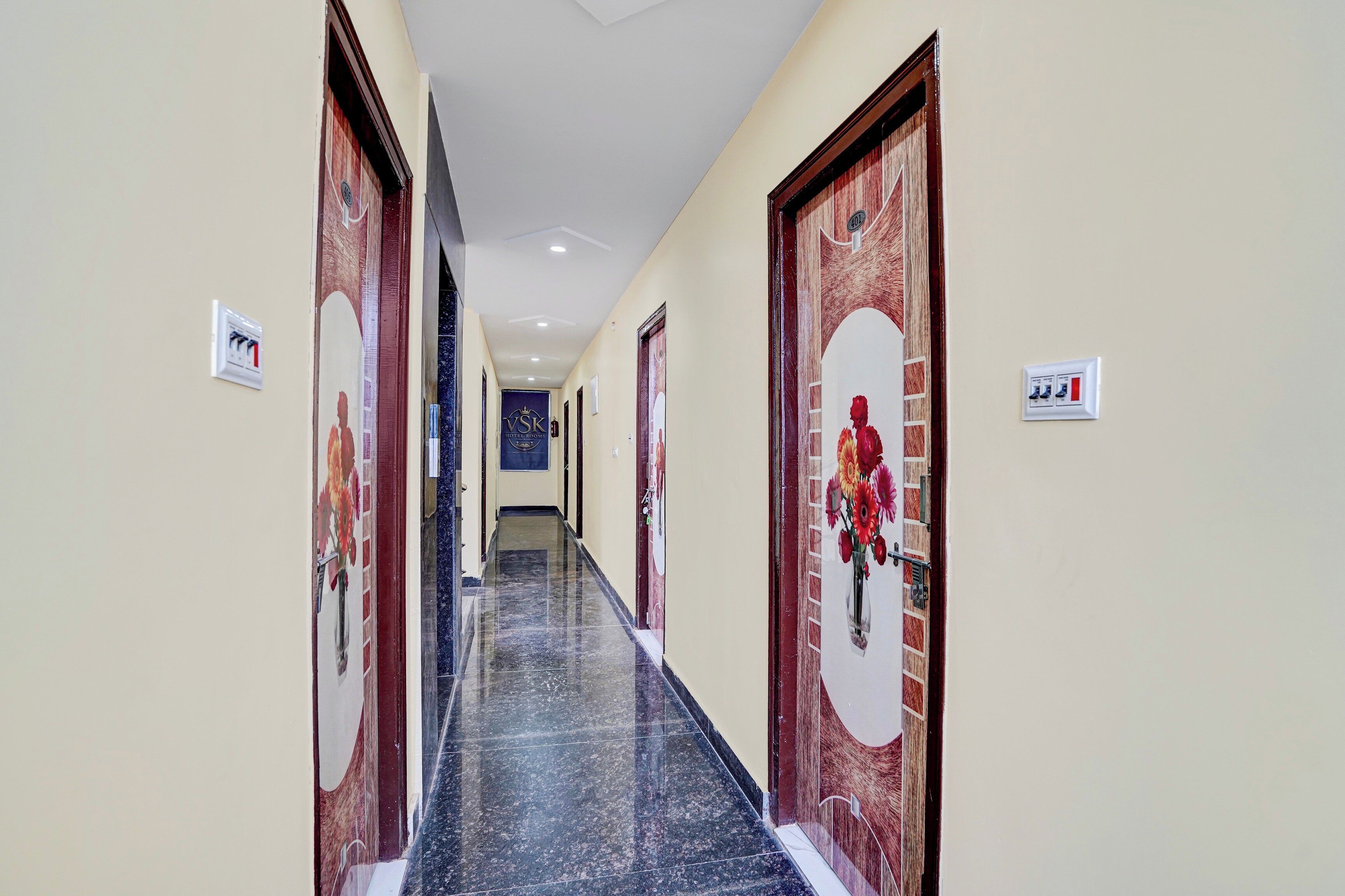 A hotel corridor with marble flooring, wooden doors, and a sign indicating the hotel rooms.