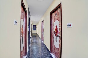 Corredor de hotel com piso de mármore, portas de madeira e uma placa indicando os quartos.