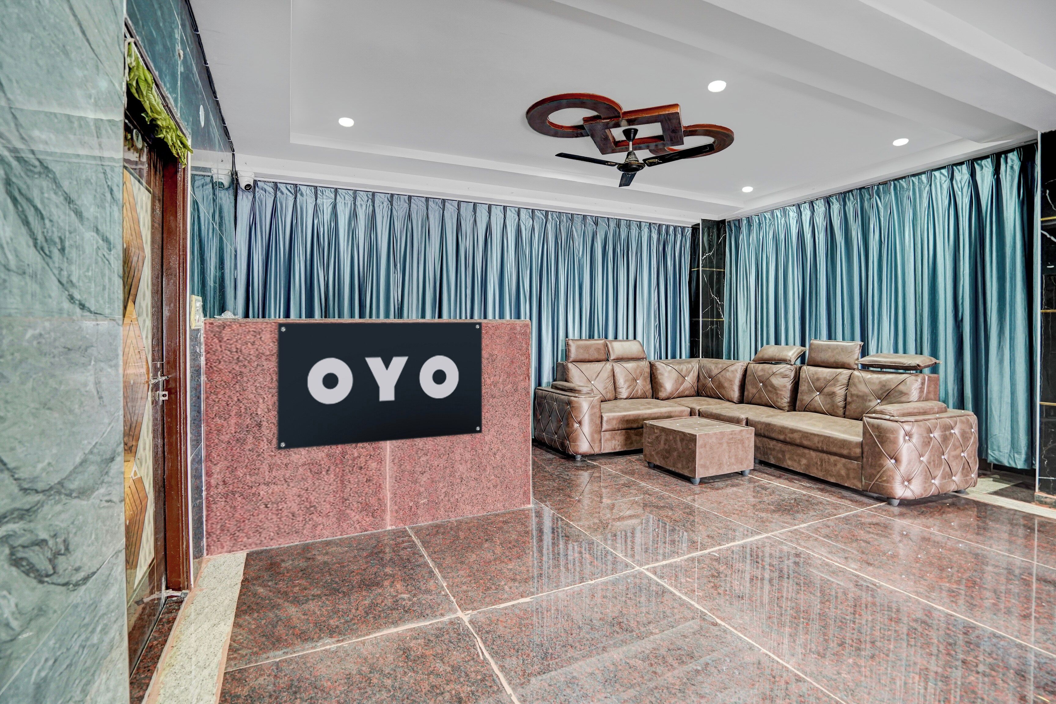 Un hall con un sofá de cuero elegante, un cartel que dice 'OYO' y un piso de mármol.