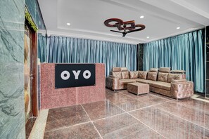 A lobby with a plush leather sofa, a sign reading 'OYO', and a marble floor.