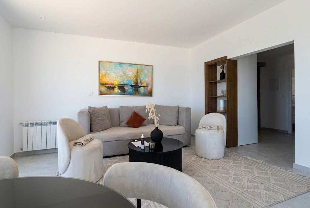A modern living room with a sofa, two armchairs, a coffee table, and a painting on the wall.
