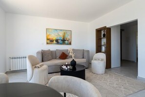 A modern living room with a sofa, two armchairs, a coffee table, and a painting on the wall. - sandra 18 (Tunis)