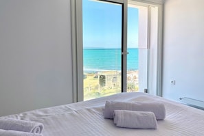 A bedroom with a large window overlooking a coastal view. - sandra 18 (Tunis)