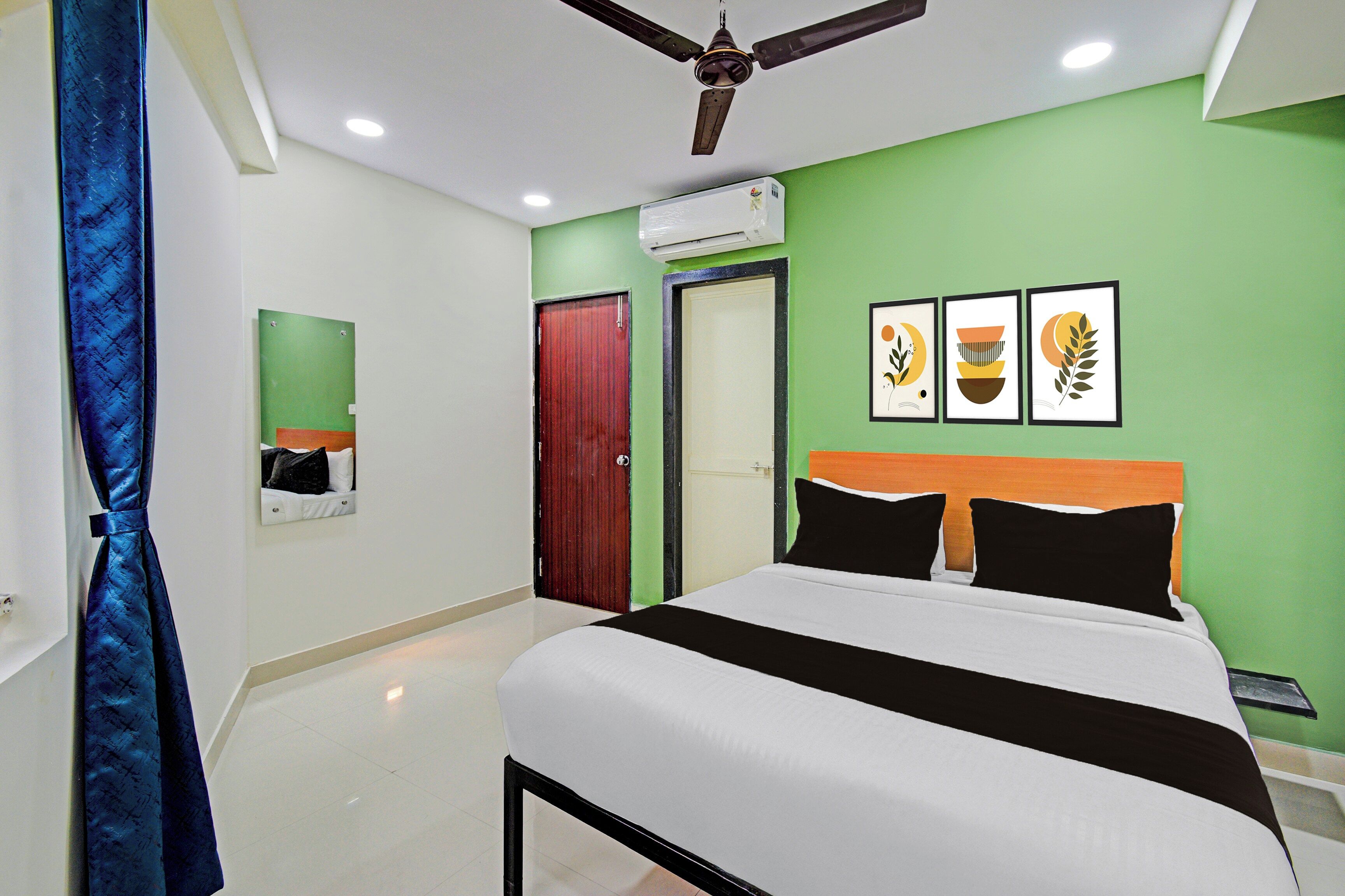 A bedroom with a bed, a ceiling fan, a door, and a wall with framed pictures.