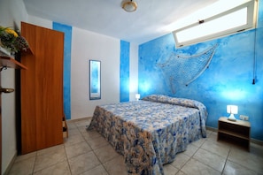 Ein Schlafzimmer mit Bett, Nachttisch, Wandhängematte, Tür und Fenster.